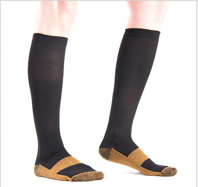 jambes d'homme portant des chaussettes de compression cuivre homme couleur noir sur fond blanc