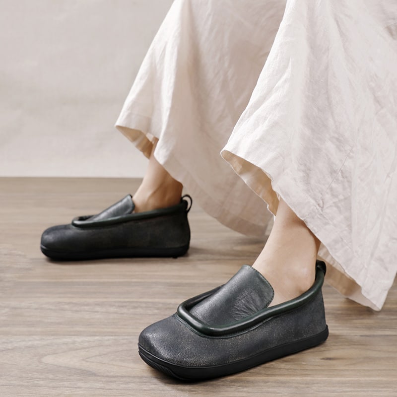 On voit les jambres d'une femme qui porte un pantalon ample en lin avec des mocassins en cuir noir à bouts carrés. Ce sont des chaussures orthopédiques.