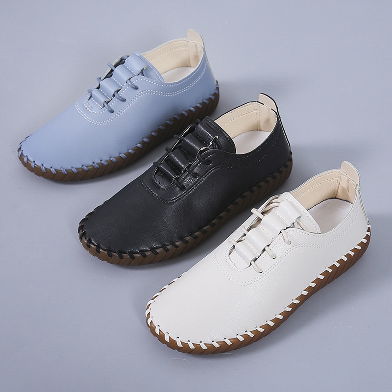 On voit trois paires de chaussures sur fond gris. Une bleue, une noire et une blanche. Elle ont une semelle en caoutchouc des des lacets de la même couleur.