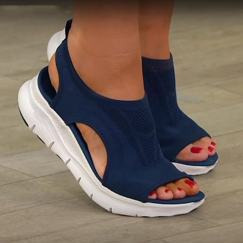 Photo de sandales orthopédiques bleues sur pieds de femmes sur sol marron gris