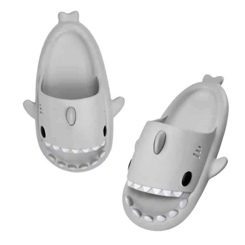 Des tongs grise en forme de requin avec des dents blanches et des yeux noir sur un fond blanc