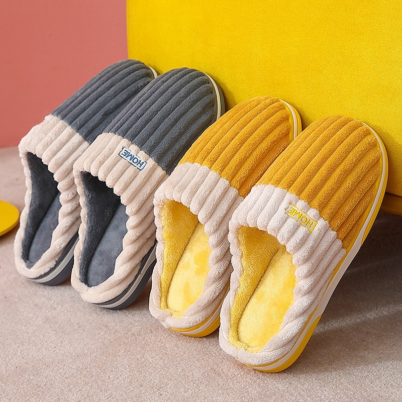 2 paires de chaussons orthopédiques gris et jaune adossés sur un mur jaune