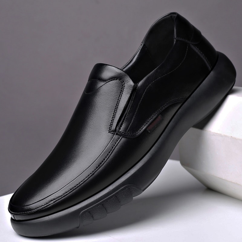 Chaussure noire pour homme posée sur un objet blanc au niveau du talon